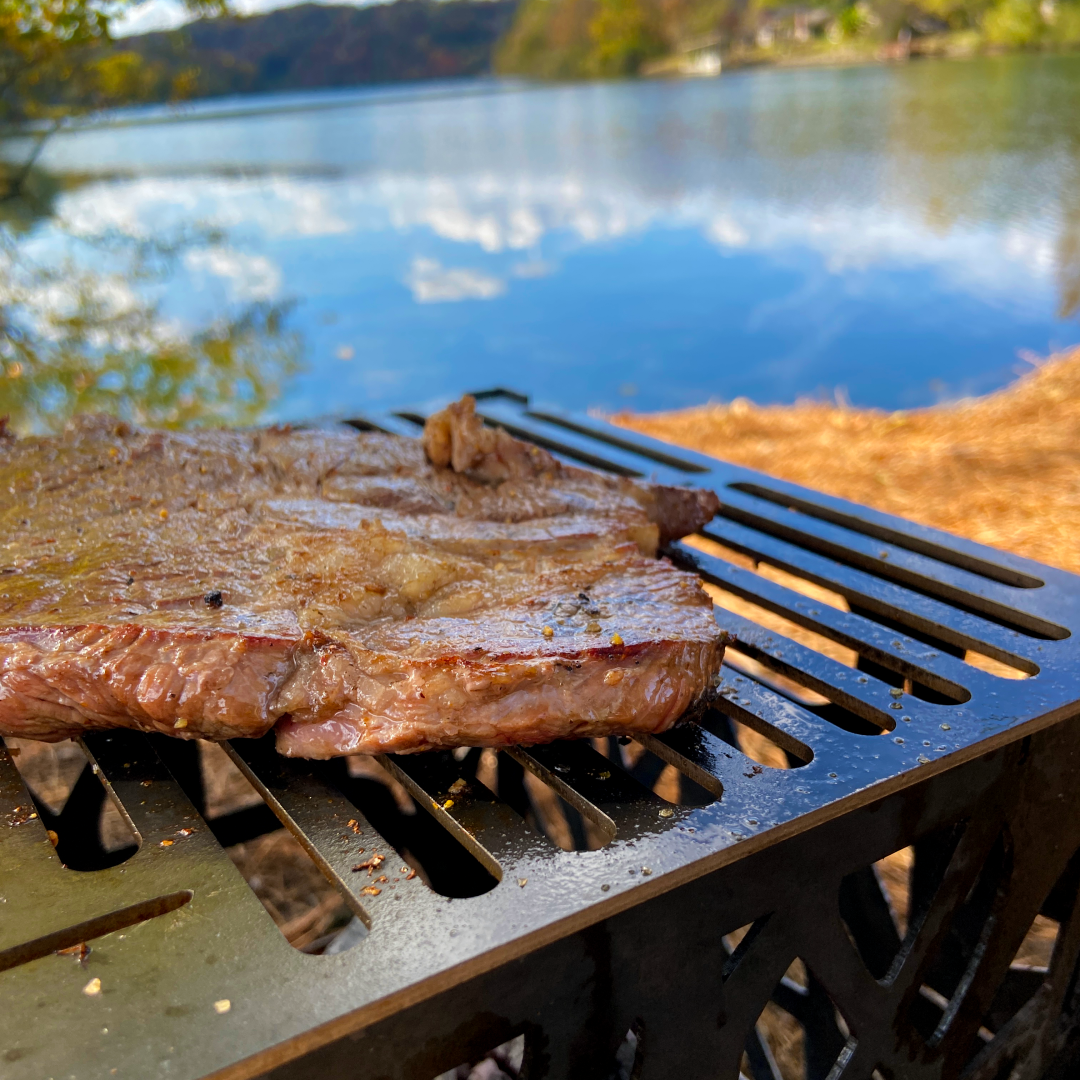 Cooking steak on campfire overlooking a lake