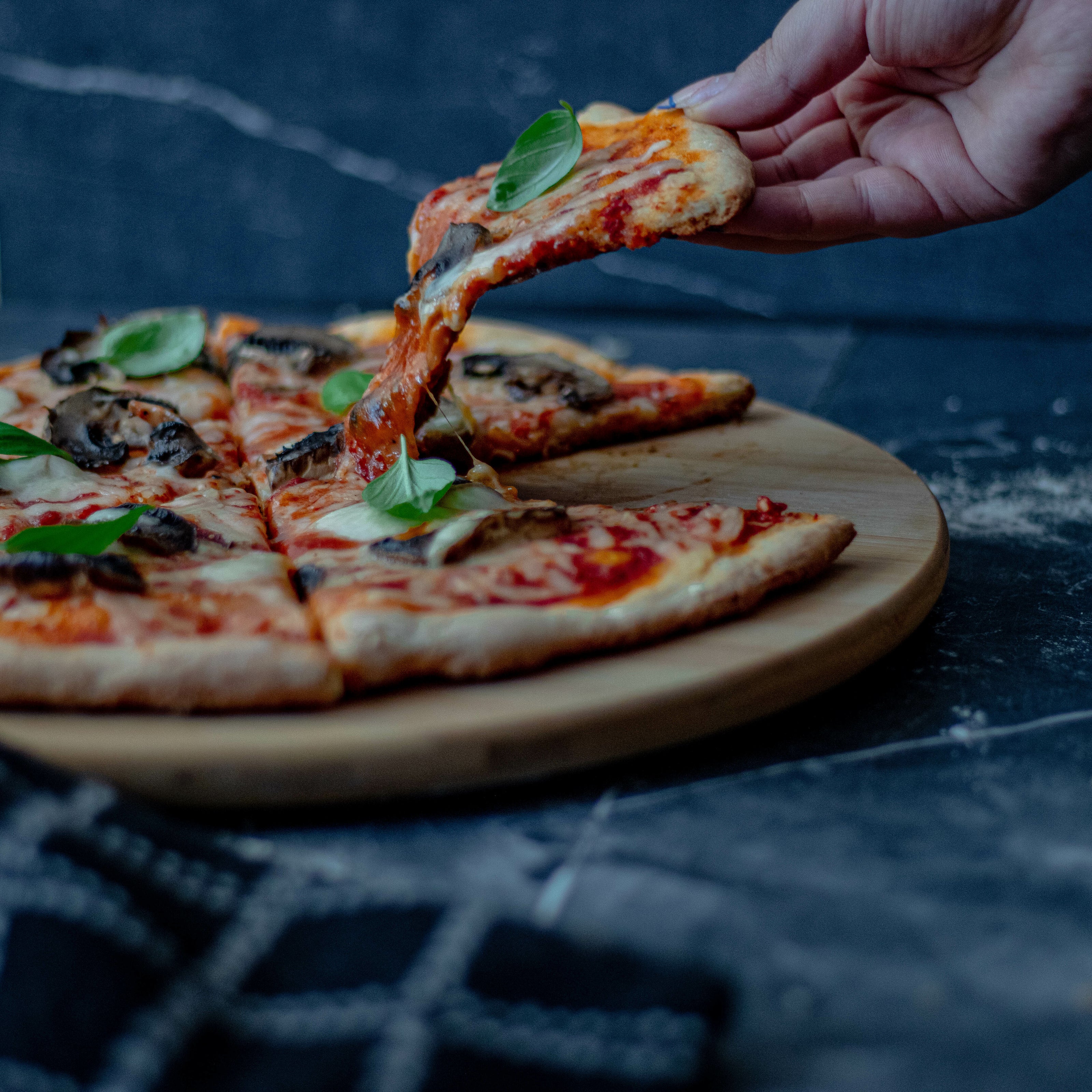 Person's hand lifting perfect slice of Doppio Living pizza